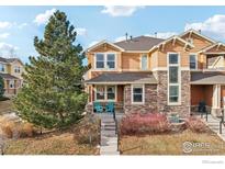 Two-story townhome with stone and siding exterior, front porch, and landscaping at 8399 Flora St # B, Arvada, CO 80005