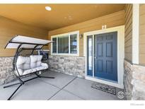 Inviting front porch with hanging chair and blue door at 1835 Virginia Dr, Fort Lupton, CO 80621