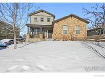 Two-story house with stone and siding exterior, snow-covered front yard at 3587 Vestal Loop, Broomfield, CO 80023