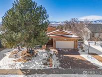 Brick ranch home with snow-covered landscaping and mountain views at 11454 W 76Th Pl, Arvada, CO 80005