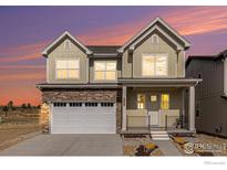 Charming two-story home featuring stone accents and a welcoming front porch at dusk at 399 Blackfoot St, Superior, CO 80027