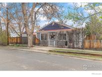 Charming single Gathering home with neutral gray siding, complemented by a red metal roof and fenced yard at 421 County Road, Louisville, CO 80027