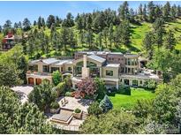 Stunning exterior view of a luxury home surrounded by lush greenery and mature trees on a hillside at 45 Bellevue Dr, Boulder, CO 80302