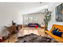 Mid-century modern living room with hardwood floors, stylish furniture, and large windows at 536 Linden Park Dr, Boulder, CO 80304
