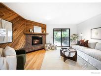 Cozy living room features a brick fireplace, wood paneling, and sliding glass doors leading to a patio at 2725 Juniper Ave # 78, Boulder, CO 80304