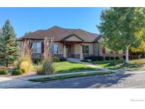 Charming home featuring a well-manicured lawn, stone accents, and mature trees at 449 Meadow View Pkwy, Erie, CO 80516