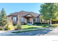 Charming single-story home with a well-manicured lawn, mature trees, and inviting stone accents at 449 Meadow View Pkwy, Erie, CO 80516