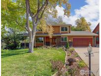 Two-story house with a red door and attached garage, featuring a well-maintained lawn and mature trees at 5375 Gunbarrel Cir, Longmont, CO 80503