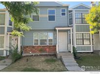 Gray townhome exterior with brick accents, steps, and small front yard at 8266 Washington St # 82, Denver, CO 80229