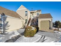 Tan exterior condo with attached garage and snow covered walkway at 2141 Sunridge Cir, Broomfield, CO 80020