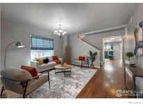 Bright living room with hardwood floors, comfy seating, and a view to the dining area at 4329 San Marco Dr, Longmont, CO 80503