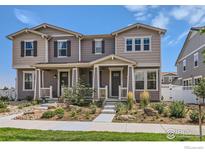 Two-story townhome with gray siding, front porch, and landscaped yard at 462 Canadian Crossing Dr, Longmont, CO 80504