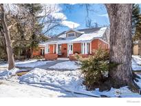 Brick home with a covered porch, landscaping, and snowy yard at 624 Maxwell Ave, Boulder, CO 80304