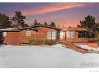 Log home exterior with large deck, snowy yard, and mountain views at 21759 Grandview Ave, Golden, CO 80401