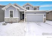 Charming two-story home with a two-car garage and stone accents in a snowy neighborhood at 3178 Beaumont Blvd, Mead, CO 80542