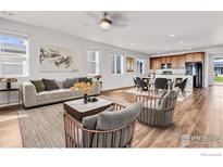 Bright, open-concept living space with hardwood floors, neutral decor, and a combined living and dining area at 6508 Copper Dr, Frederick, CO 80516