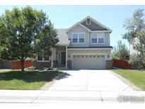 Two-story house with a gray and beige exterior, attached garage, and landscaped yard at 12609 Jersey W Cir, Thornton, CO 80602