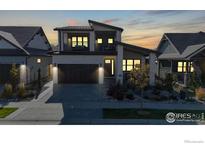 Modern two-story home showcasing elegant stonework, a balcony, a dark wood garage door, and a well-manicured front yard at 3364 Danzante Bay Ct, Berthoud, CO 80513