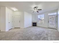 Bright living room featuring a cozy fireplace, ceiling fan, neutral paint, and large windows at 5756 N Genoa Way # 205, Aurora, CO 80019