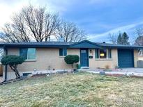 Charming single-story home featuring a blue door and attached garage with drought tolerant landscaping at 6487 Eaton St, Arvada, CO 80003