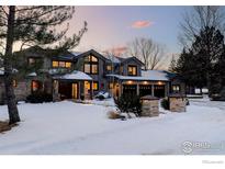 Charming exterior showcasing a three-car garage, beautiful brickwork, and mature trees in a snowy landscape at 7035 Rustic Trl, Boulder, CO 80301