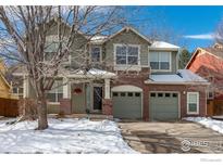 Two-story house with brick and siding, two-car garage, and snowy front yard at 811 Vireo Ct, Longmont, CO 80504