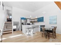 Modern kitchen with teal cabinets, stainless steel appliances, and an island with seating at 836 Walnut St # E, Boulder, CO 80302