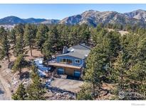 Stunning aerial view of a house nestled in a mountainous area with a large deck at 8393 Stoneridge Ter, Boulder, CO 80302