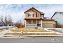 Two-story house with tan siding, red accents, and a porch at 9821 Mobile St, Commerce City, CO 80022