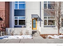 Modern two-story home with a yellow front door and white picket fence at 105 N Iowa Ave, Lafayette, CO 80026