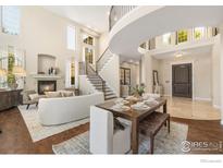 Living room with a fireplace and staircase, adjacent to a dining area at 1644 Stardance Cir, Longmont, CO 80504