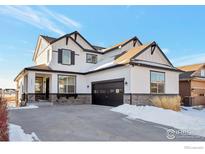 Two-story house with white siding, dark garage door, and stone accents at 16636 W 94Th Dr, Arvada, CO 80007