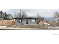 Cute ranch home with gray exterior, wood fence, and landscaped yard at 305 S Carr St, Lakewood, CO 80226