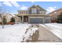 Two-story house with gray siding, three-car garage, and snowy front yard at 3183 Starry Night Loop, Castle Rock, CO 80109