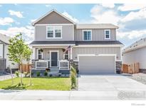 Two-story house with gray siding, a gray door, and a landscaped front yard at 14703 Guernsey Dr, Mead, CO 80542