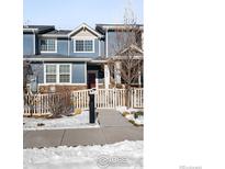 Two-story townhome with blue siding, white trim, and a fenced front yard at 257 Jackson Dr, Erie, CO 80516