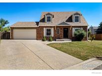 Charming brick home featuring a well-manicured lawn and an attached two-car garage at 719 Marshall Pl, Berthoud, CO 80513