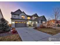 Two-story home with gray siding, a three-car garage, and landscaping at 864 Dakota Ln, Erie, CO 80516