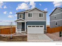 Two-story house with gray and blue siding, white garage door, and a wooden fence at 889 Crest St, Lochbuie, CO 80603