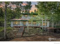 Two-story house with wood deck and stairs, nestled in a wooded area at 11957 Brook Rd, Golden, CO 80403