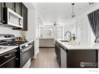 Modern kitchen features stainless steel appliances, dark cabinets, and a large island with quartz countertops at 5335 Spalding Pl, Frederick, CO 80504