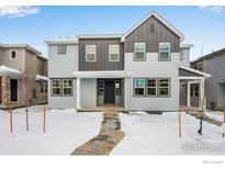 Charming two-story home showcasing modern architecture, neutral colors, and a welcoming entrance on a snow-covered lawn at 1423 Great Western Dr, Longmont, CO 80501