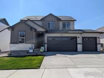 New construction two-story home with a three car garage, stone accents, and well manicured front lawn at 16815 Mckay Dr, Mead, CO 80542