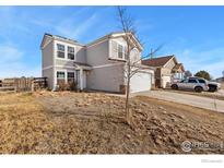Two story home featuring neutral siding, brick accents, two car garage and a partially xeriscaped yard at 177 Westin Ave, Brighton, CO 80603