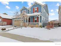 Charming two-story home featuring a welcoming front porch and a well-maintained yard with wintery landscape at 1845 Pioneer Cir, Lafayette, CO 80026