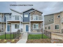 New construction townhome with a stone facade, balcony, and small yard at 2734 Bear Springs Cir, Longmont, CO 80503