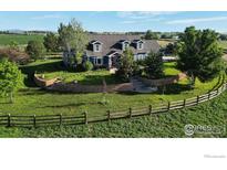 Stunning blue two-story home boasts immaculate landscaping, a spacious lawn and wooden fence at 483 E State Highway 56, Berthoud, CO 80513