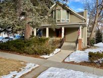 Charming two-story home with a covered front porch, lush landscaping, and an American flag at 1114 4Th Ave, Longmont, CO 80501