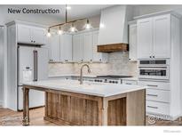 New kitchen with white cabinets, wood island and modern stainless steel appliances at 1233 Eliza Ave, Berthoud, CO 80513
