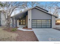Modern home featuring a glass garage door, gray wood siding, and covered front porch at 2201 Juniper Ct, Boulder, CO 80304